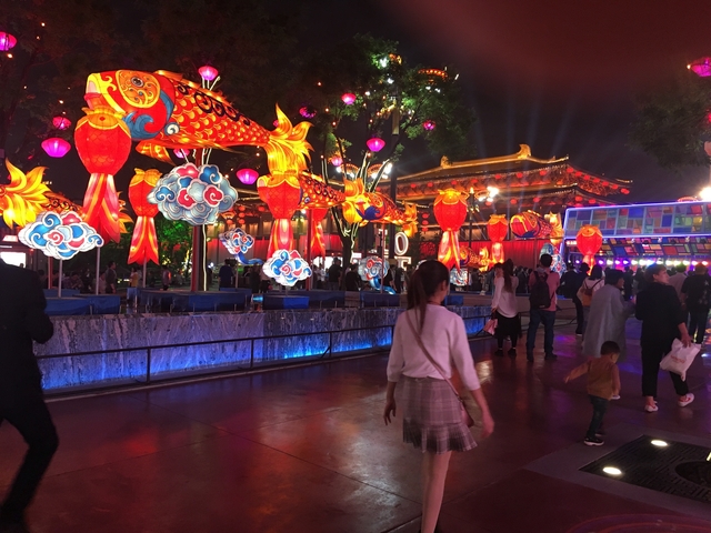 Vibrant night scene with people and large colorful decorations.