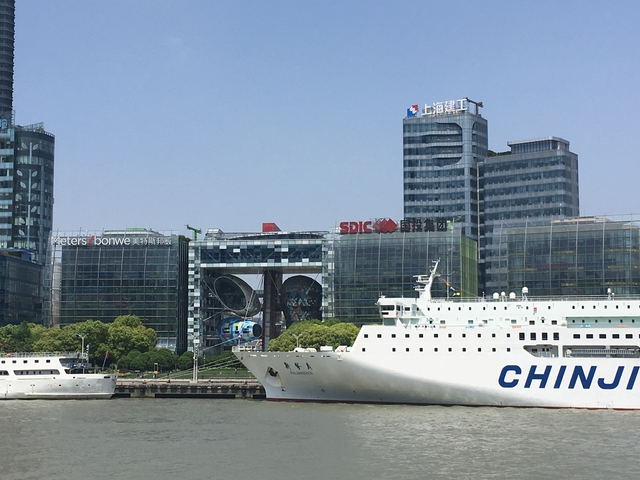      Boats on a river with city buildings in the background.
  