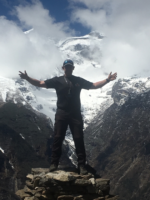       Man posing with arms outstretched in front of snowcapped mountains
  