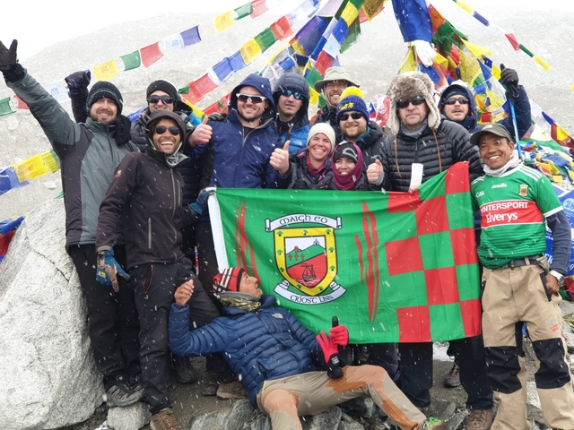       Group of trekkers with a flag and colorful prayer flags
  