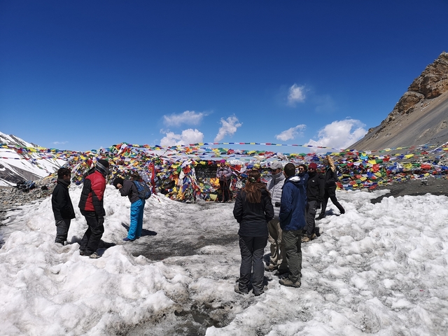 Group of trekkers at a mountain pass with prayer flags