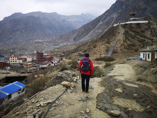 Person with a backpack overlooking a mountain village