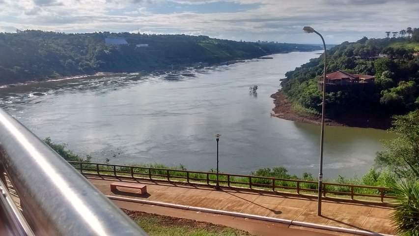A scenic river view with greenery on both sides and a pathway.