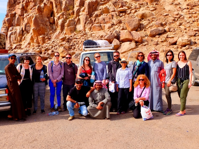 A group of people posing in front of rugged rocky scenery.