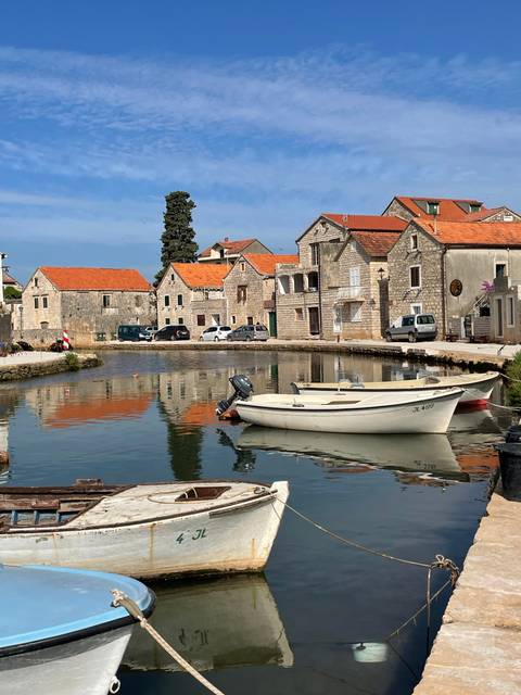       Docked boats in a quaint harbor with stone houses.
  