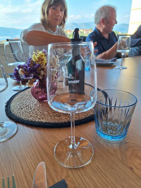       A dining table setting with a glass and a bottle of wine.
  