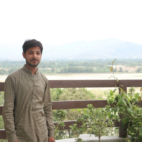       Man standing on balcony overlooking a scenic landscape.
  