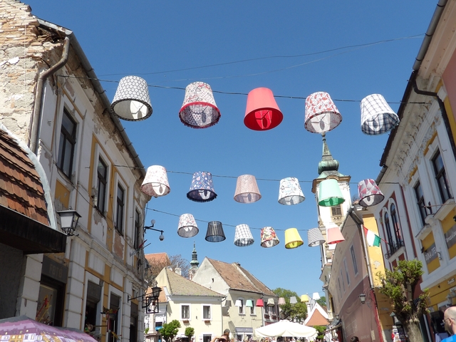       Street with colorful lamps hanging between historic buildings.
  