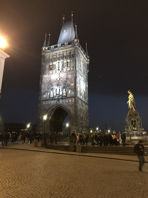 Historic bridge at night with illuminated statue.