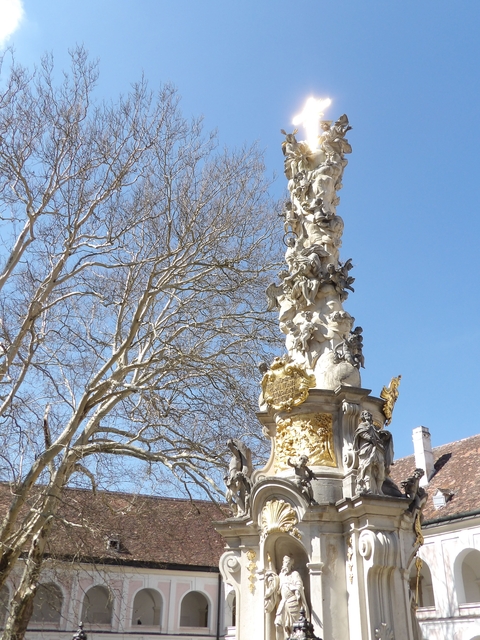       Decorative column with intricate sculptures, set against a blue sky.
  
