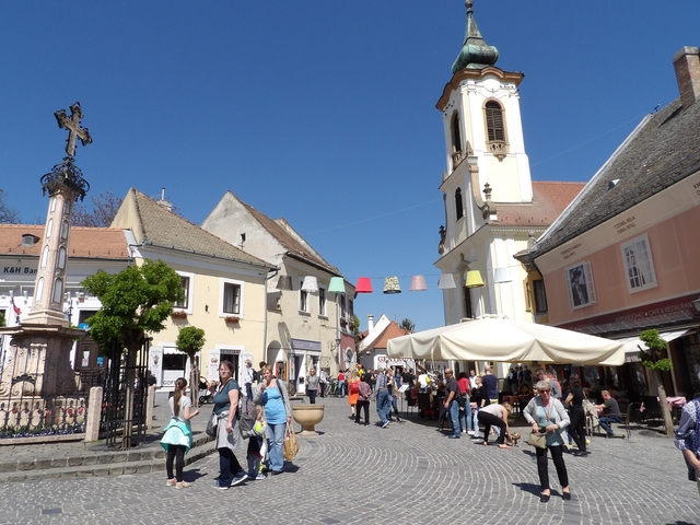 Bustling town square with historical buildings and a church.
