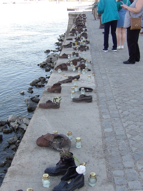 Shoes on the Danube Bank memorial with candles and flowers.