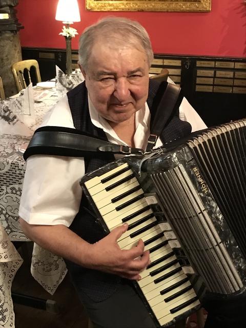       Man playing an accordion at a social gathering.
  