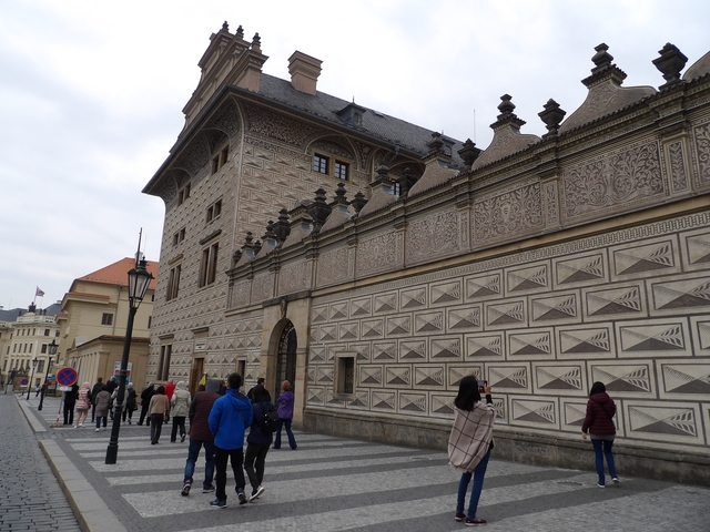       People walking along a street with historic buildings.
  