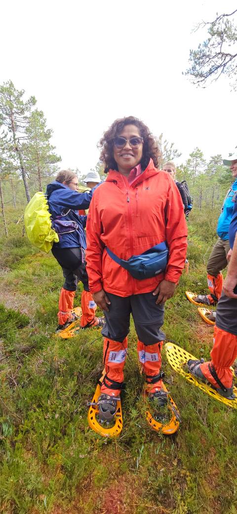       People wearing snowshoes in a forest setting.
  