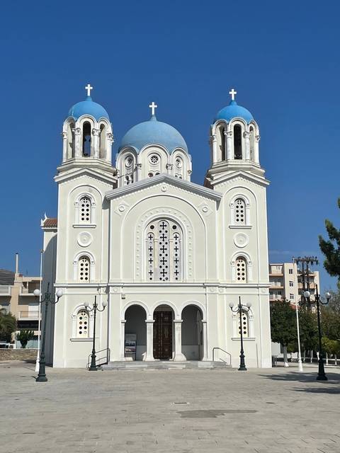      White church with blue domes and crosses.
  