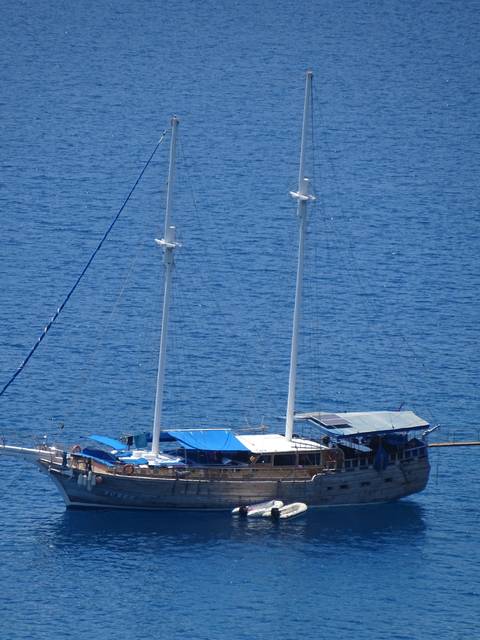       Large boat with sails docked on the sea.
  