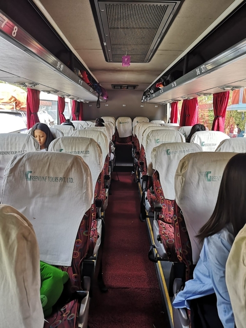 Interior of a tour bus with empty seats and few passengers.