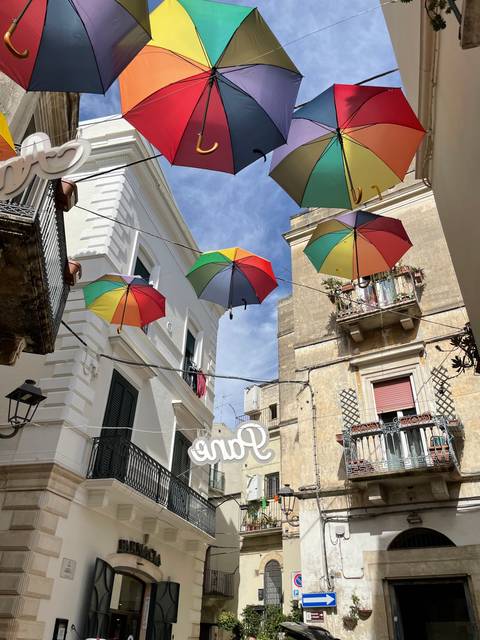       Colorful umbrellas hanging over a narrow street.
  