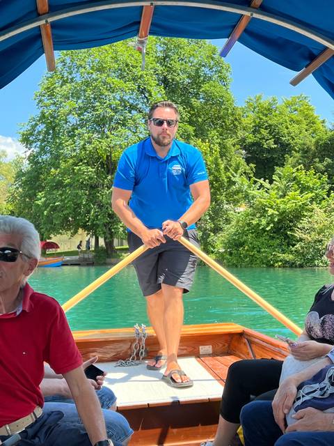       Man standing on a boat in a river or lake.
  