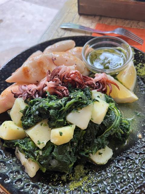       Squid dish with potatoes and greens on a plate.
  