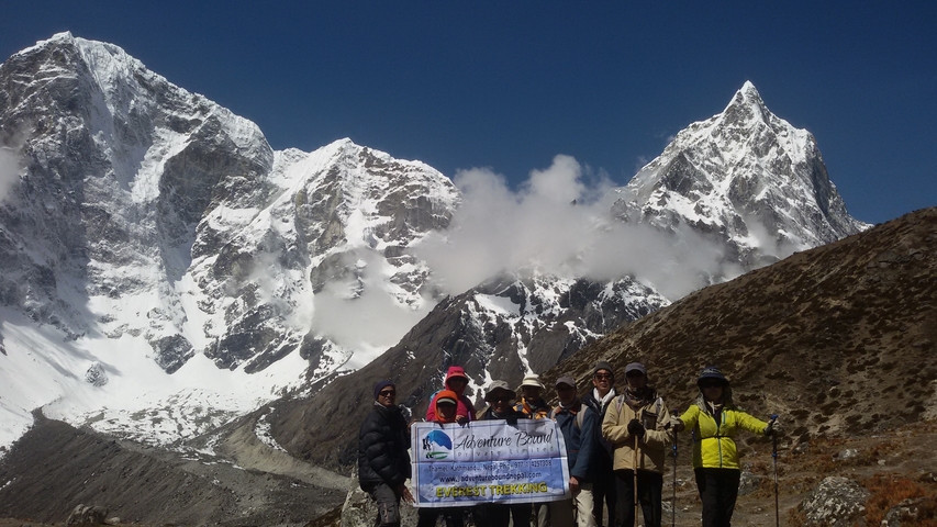 Group of hikers with a banner in front of snow-capped mountains.