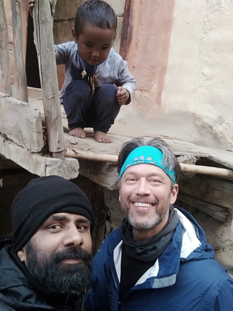       Group of people, one sitting on a rustic structure.
  