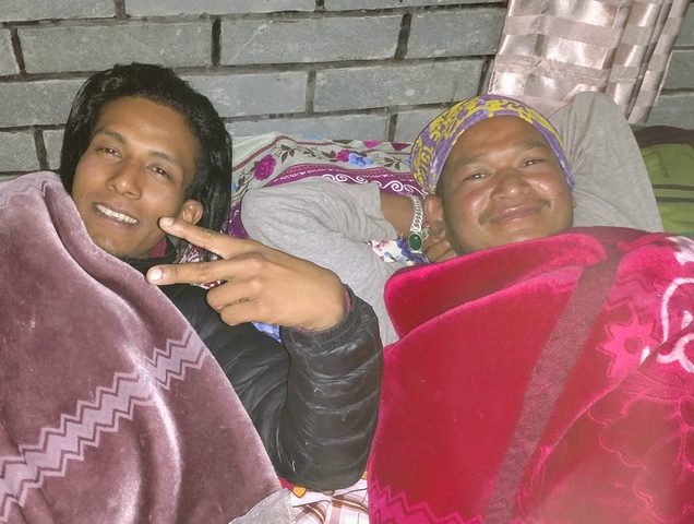       Two people relaxing indoors covered with blankets.
  