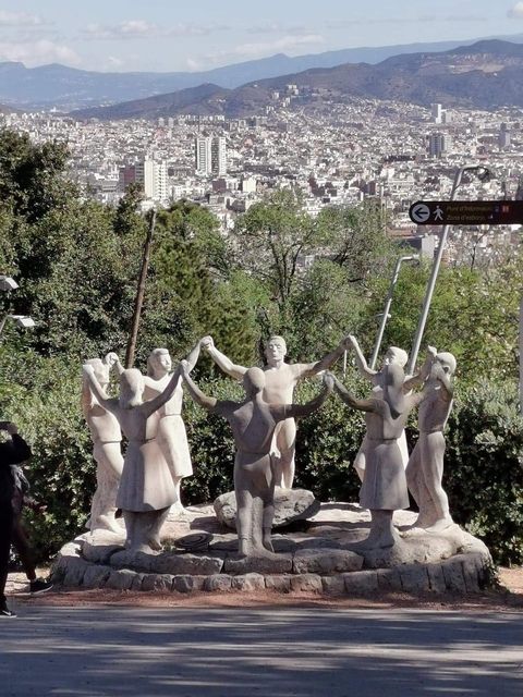 Stone statue of people holding hands in a circle surrounded by greenery.