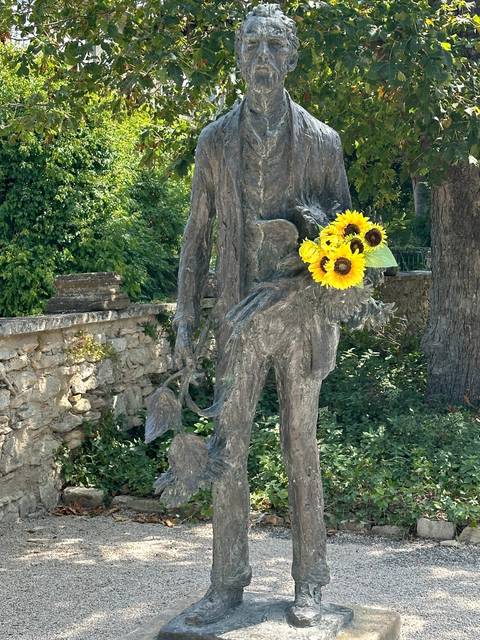Statue holding a bouquet of sunflowers.