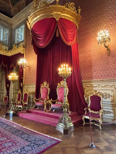 Luxurious palace interior with ornate red curtains and furniture.
