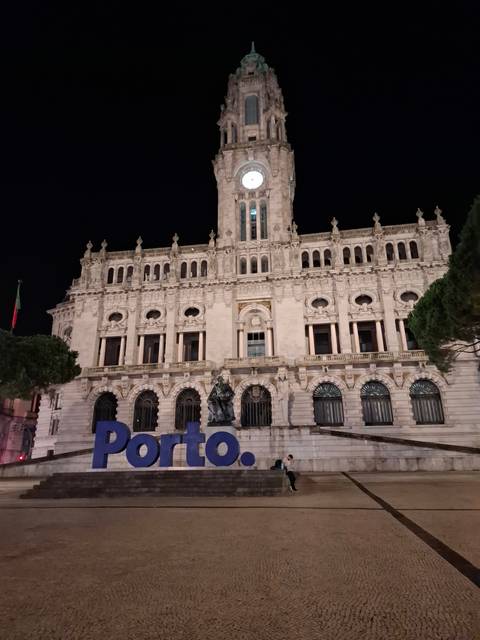 Historic building lit up at night with Porto sign.