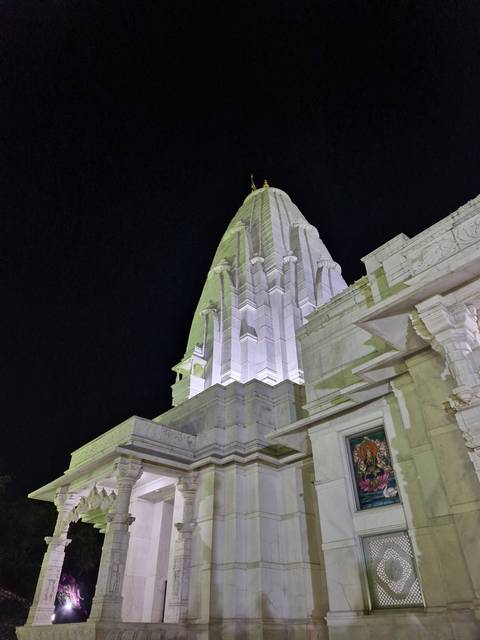 Temple lit at night with detailed carvings visible.