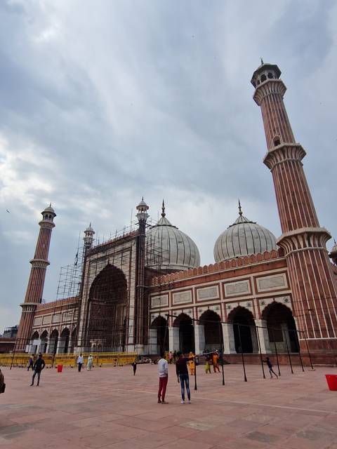       Tourists visiting Jama Masjid, a large mosque with elegant red sandstone architecture.
  