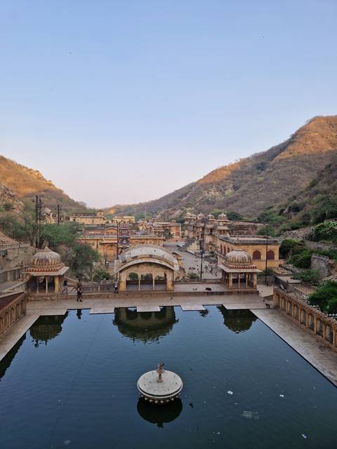 Beautiful temple by a water body with hills in the background.