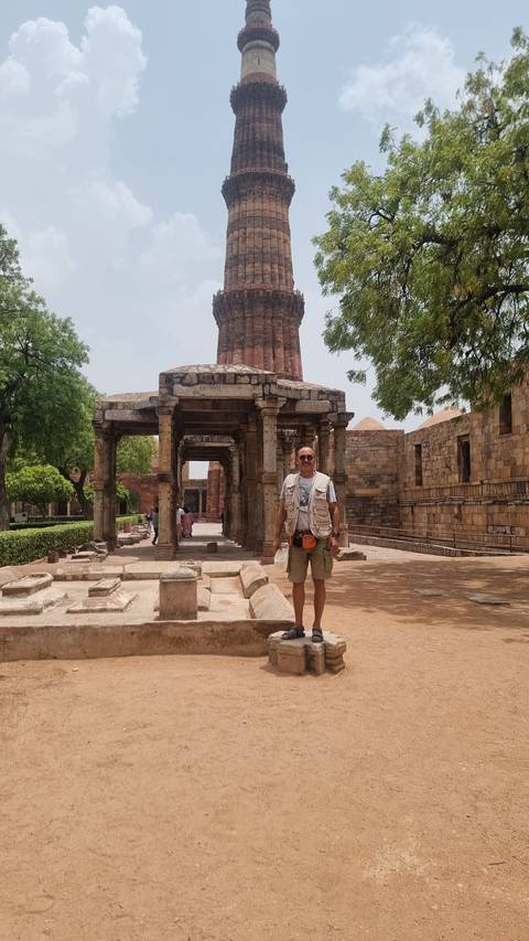       Traveler posing in front of Qutub Minar.
  