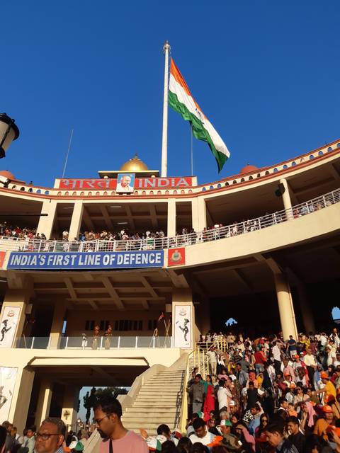       A large crowd gathered in front of a monument with an Indian flag.
  