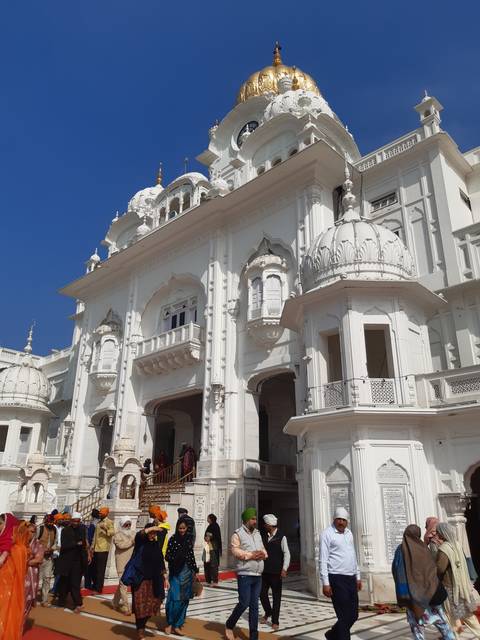       A group of people near a white temple building.
  