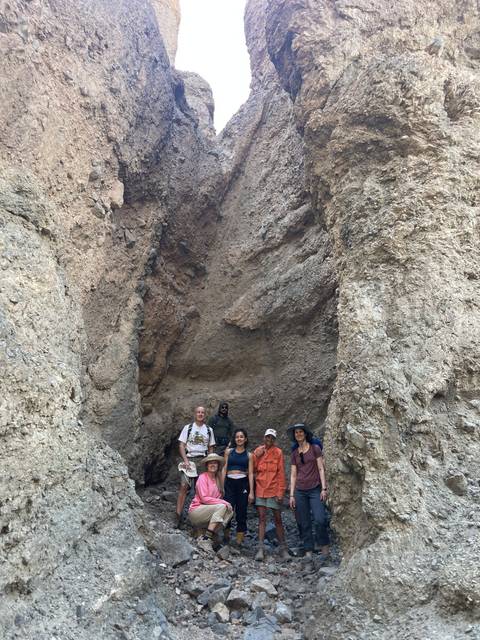       A group of people posing inside a rocky enclosure.
  