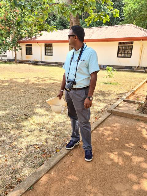 Person standing with camera and straw hat.