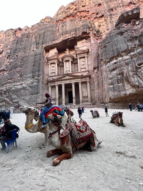       People with camels in front of Petra's Treasury.
  