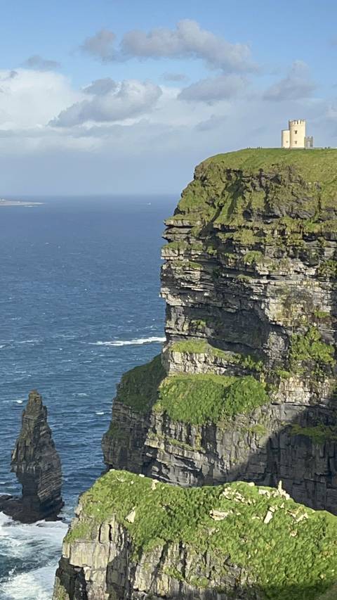       Cliffs of Moher with a tower, towering over the ocean.
  
