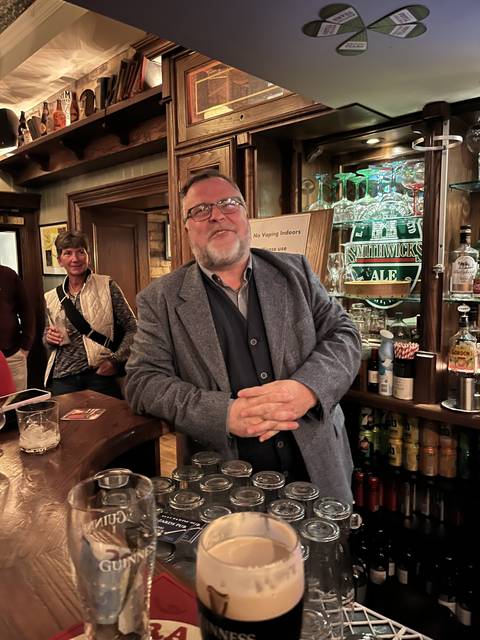 A man at a bar with beer glasses.