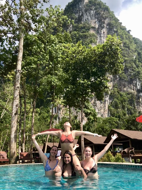 Person relaxing on a hammock with trees and cliffs in the background.