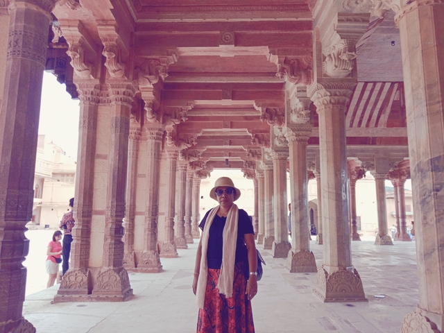 Person standing under decorative stone arches with columns.