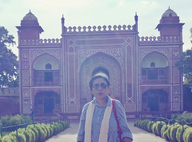 Person posing in front of a large decorative gate.