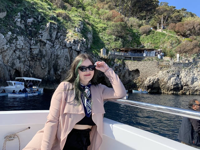 Woman on a boat enjoying a view of rocky coastline.
