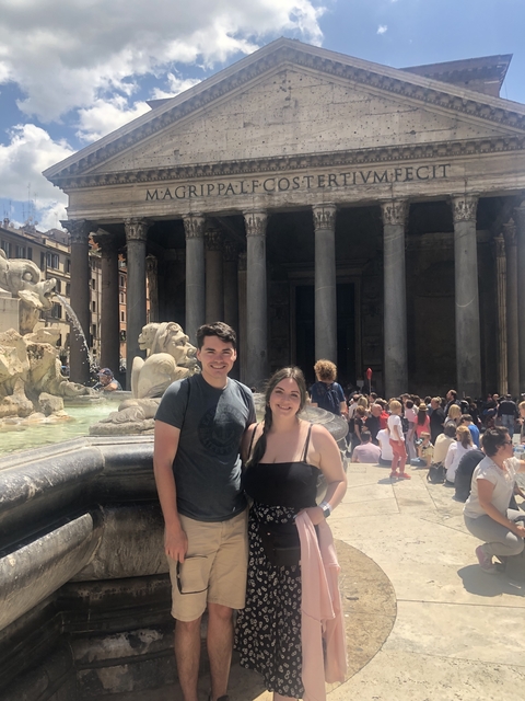 Two people posing in front of a historical building with columns.