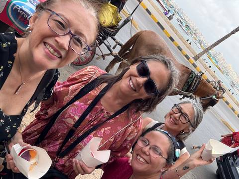 Four women posing with a carriage and driver.