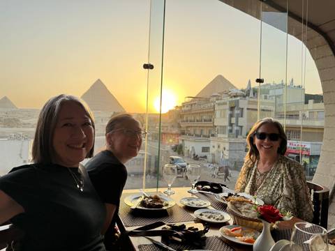 Three women dining with a view of the Pyramids.